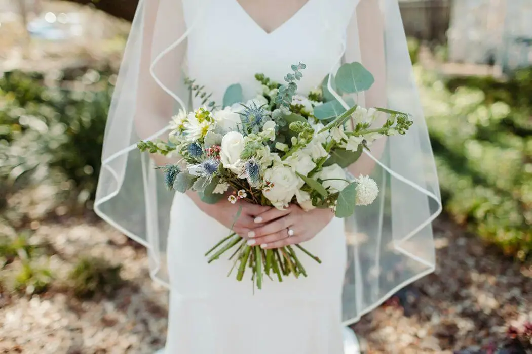 Bride holding a white flower bouquet featuring one of the top 2026 wedding makeup trends soft glam.